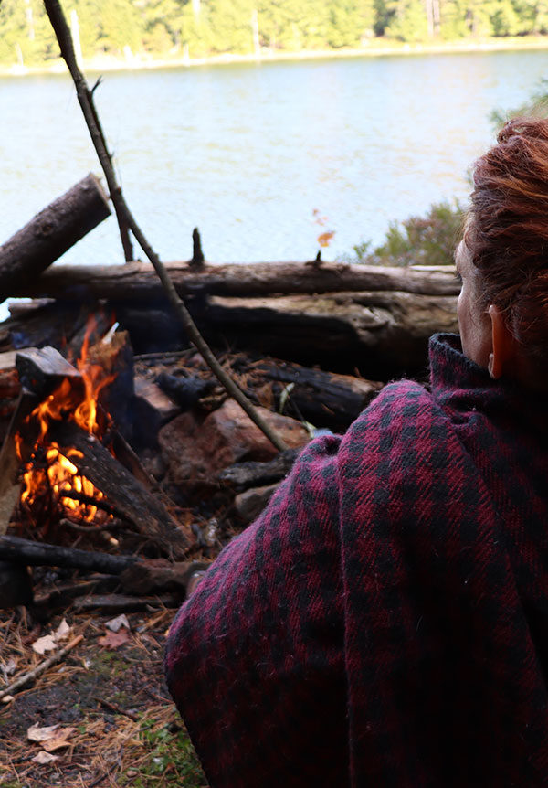 Woman sitting by a fire at Adirondack lake