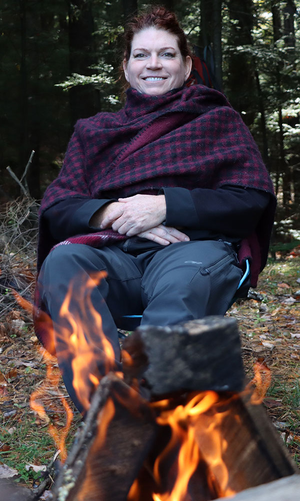 Woman in front of Adirondack camp fire