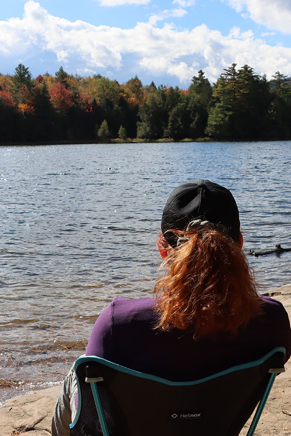 Woman looking over adirondack pond in Autumn